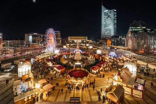 birds view over the Christmas market in Leipzig located at Augustusplatz with decorated stall allocated in a circle, a carousel, christmas tree and a ferries wheel. The MDR tower is visible in the back of the picture