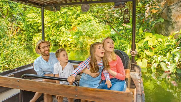 Familie mit zwei Kindern sitzt im Floß, welches durch das Gondwanaland im Leipziger Zoo fährt. Die Kinder sind begeistert und strahlen um die Wette.