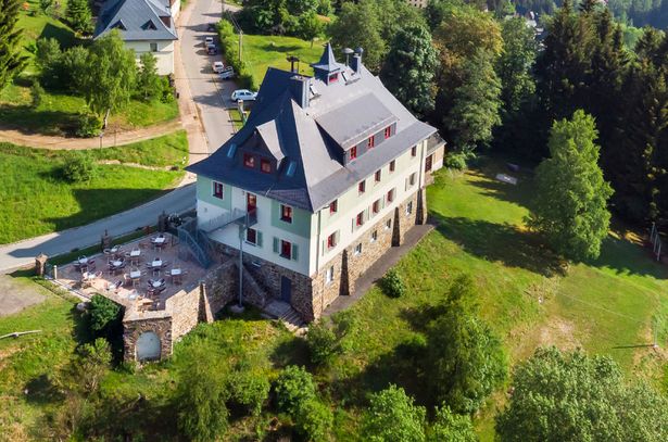 Die Jugendherberge Johanngeorgenstadt von außen fotografiert. Man sieht eine große Terrasse und das Gebäude.