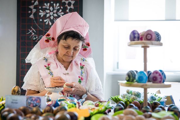 Sorbian woman in a traditional outfit decorating Easter eggs